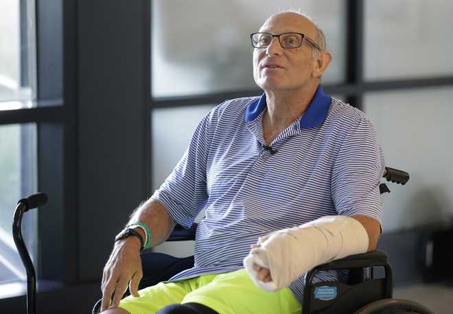 William Lytton, of Scarsdale, N.Y., is seated in a wheelchair while taking a break from physical therapy at Spaulding Rehabilitation Hospital, in Boston, Tuesday, Aug. 28, 2018, while recovering from a shark attack. Lytton suffered deep puncture wounds to his leg and torso after being attacked by a shark on Aug. 15, 2018 while swimming off a beach, in Truro, Mass. Lytton injured a tendon in his arm while fighting off the shark. (AP Photo/Steven Senne)