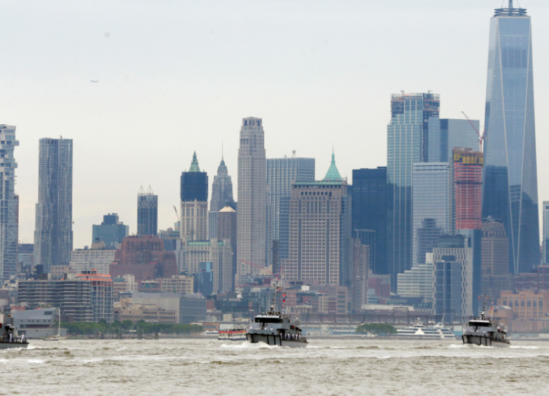 Ships from the maritime services and their escorts make their way past lower Manhattan in New York as seen from Weehawken N.J. Wednesday