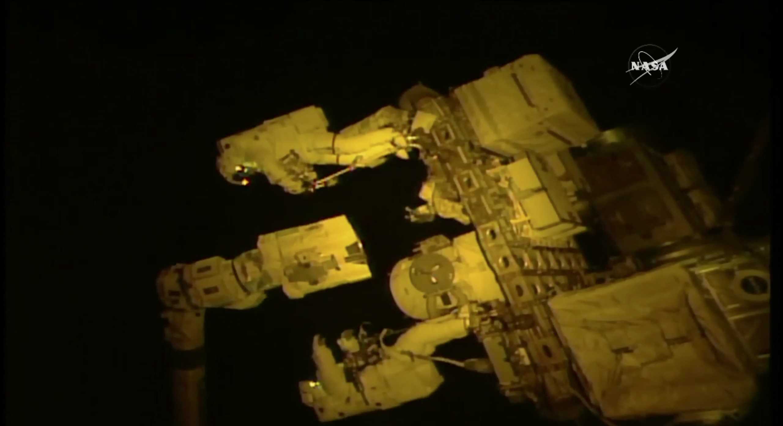 Spacewalking astronauts give a hand to robot arm