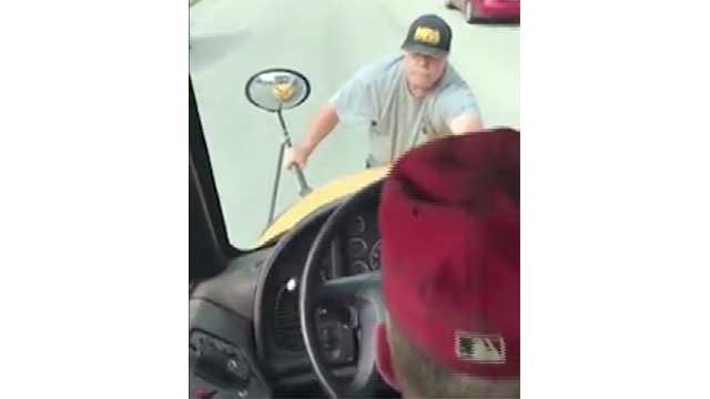 Video shows man clinging to moving school bus