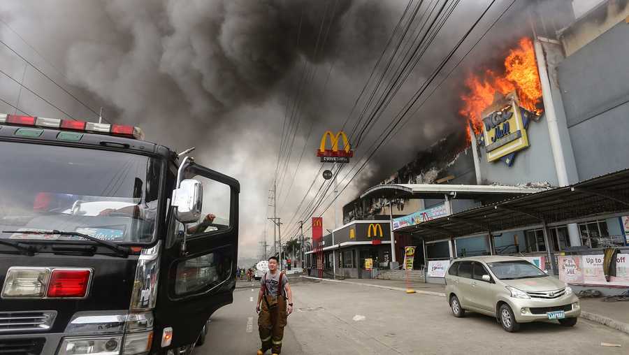 This photo shows a firefighter standing in front of a burning shopping mall in Davao City, on the southern Philippine island of Mindanao.