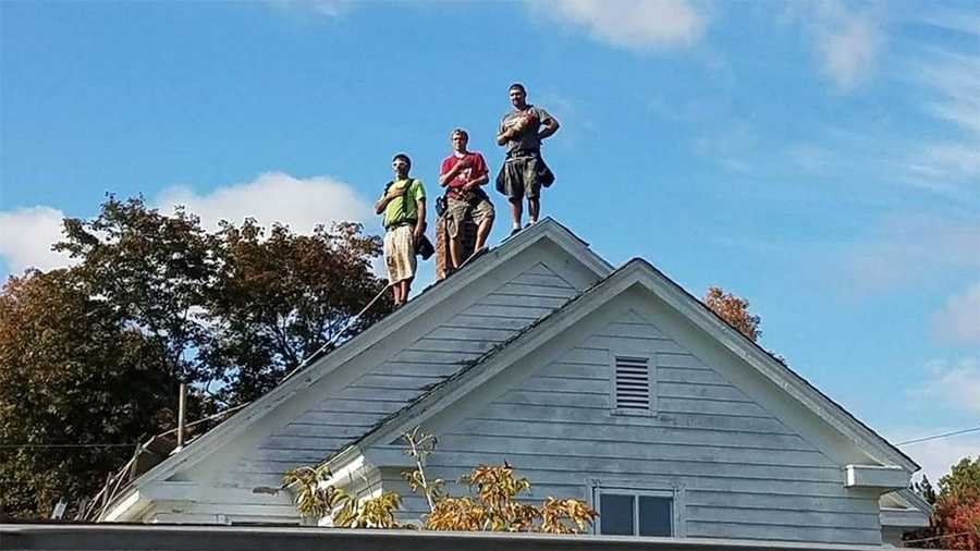 Roofers pause for national anthem played at nearby football game