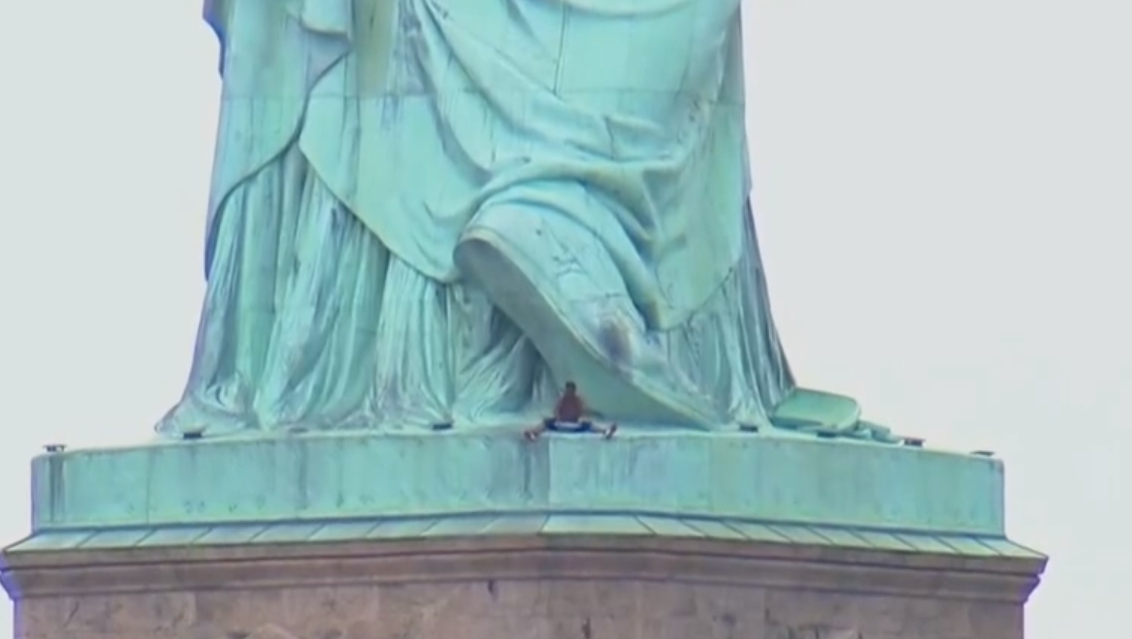 Image result for A woman who climbed up to the robes of the Statue of Liberty to protest the separation of migrant families