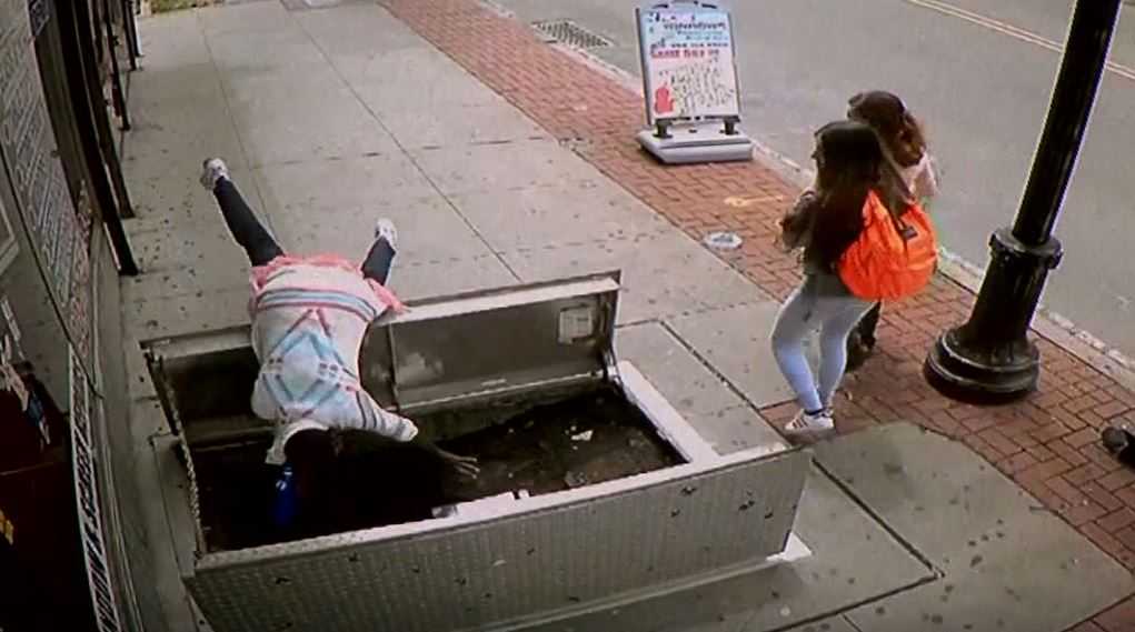 Caught on camera: Woman distracted by cellphone falls down cellar door